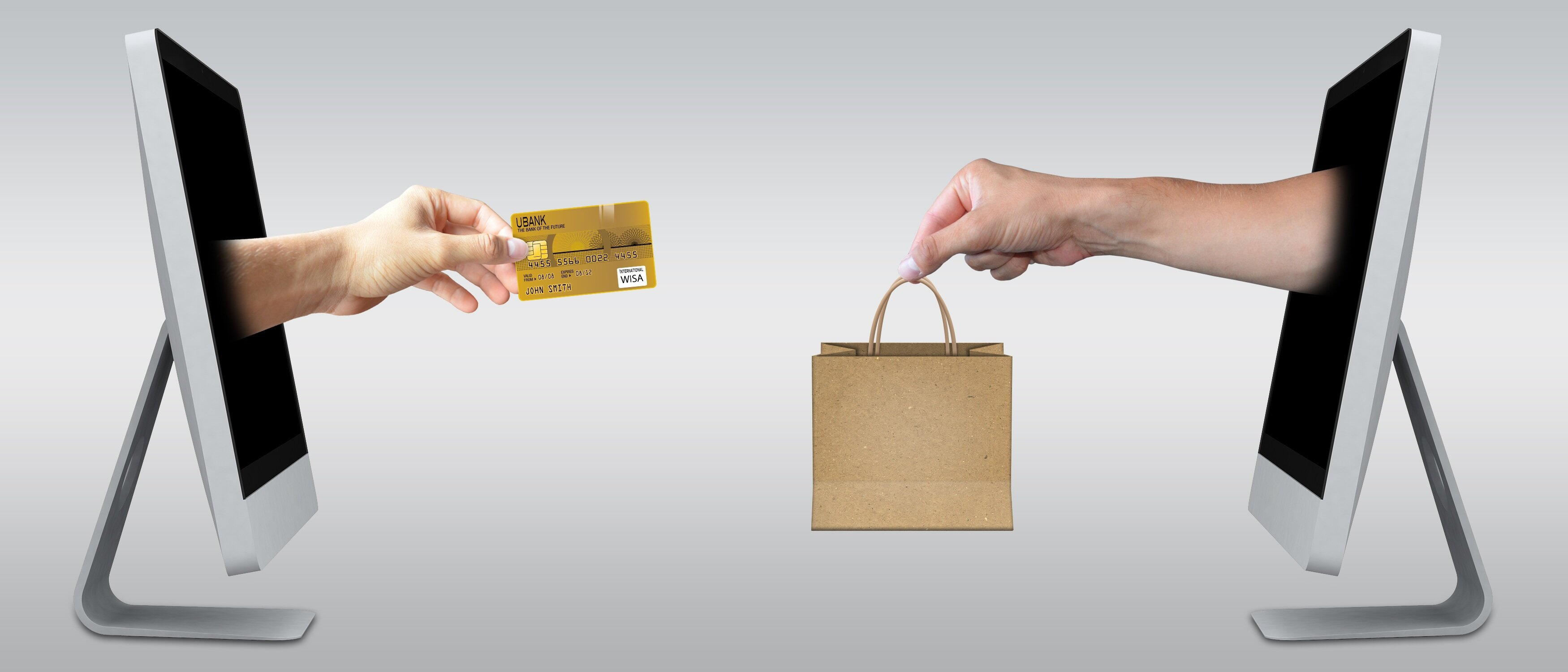 Uma mão saindo de um monitor à esquerda, entregando um cartão de crédito à outra mão, que segura uma sacola, à direita